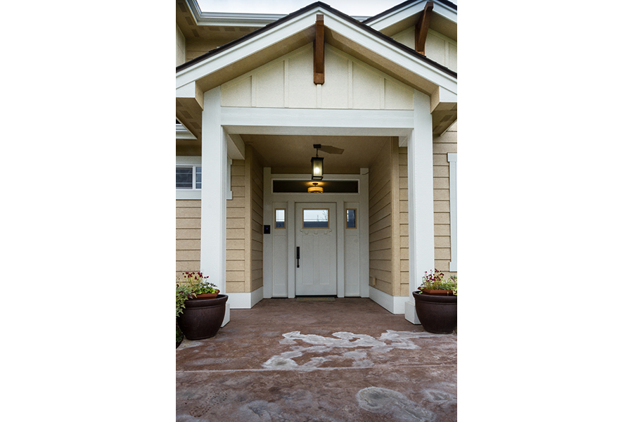 A deep porch with a heavy roof overhang provides a zero-step entry into home, shielded from the elements.